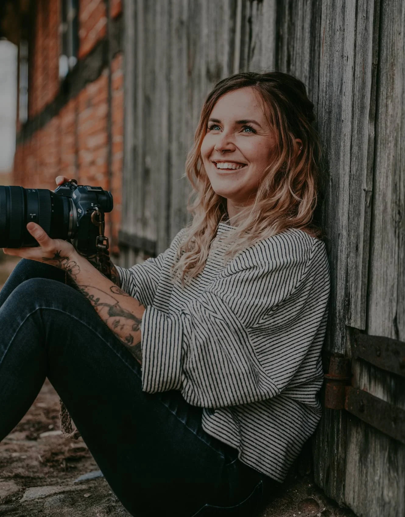 Fotografin mit Kamera vor Holzwand